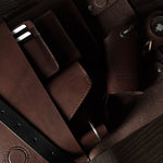 Close-up of a brown leather bag with straps on a wooden surface