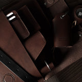 Close-up of a brown leather bag with straps on a wooden surface