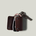 Dark brown leather key holder with 2 metal buttons, showing car key fob and key on light grey background