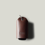 Dark brown leather key holder with keyring on light grey background