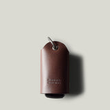 Dark brown leather key holder with keyring on light grey background