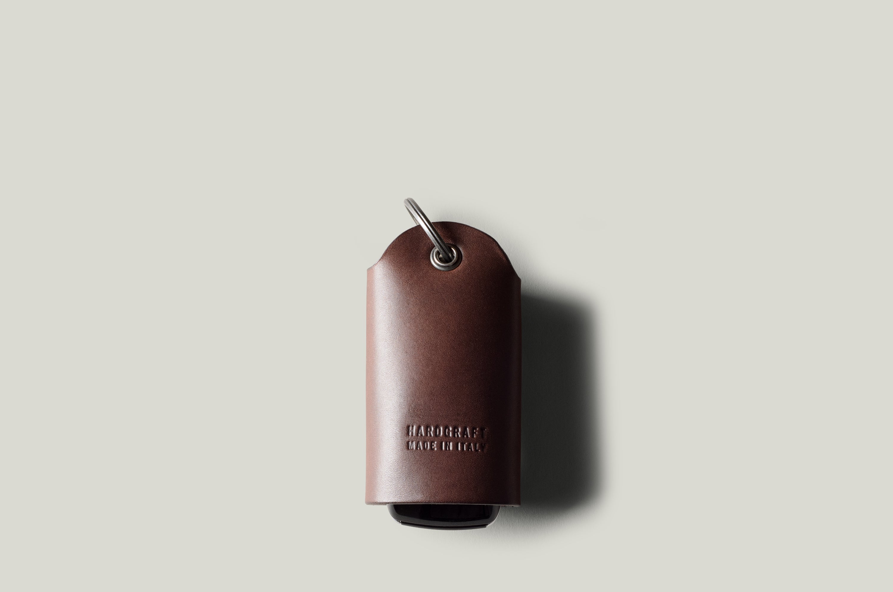 Dark brown leather key holder with keyring on light grey background