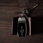 Dark brown leather key holder with keyring, key and car key fob on wood background