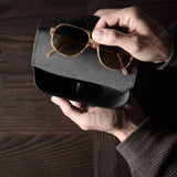 Black leather glasses case with sunglasses in hand