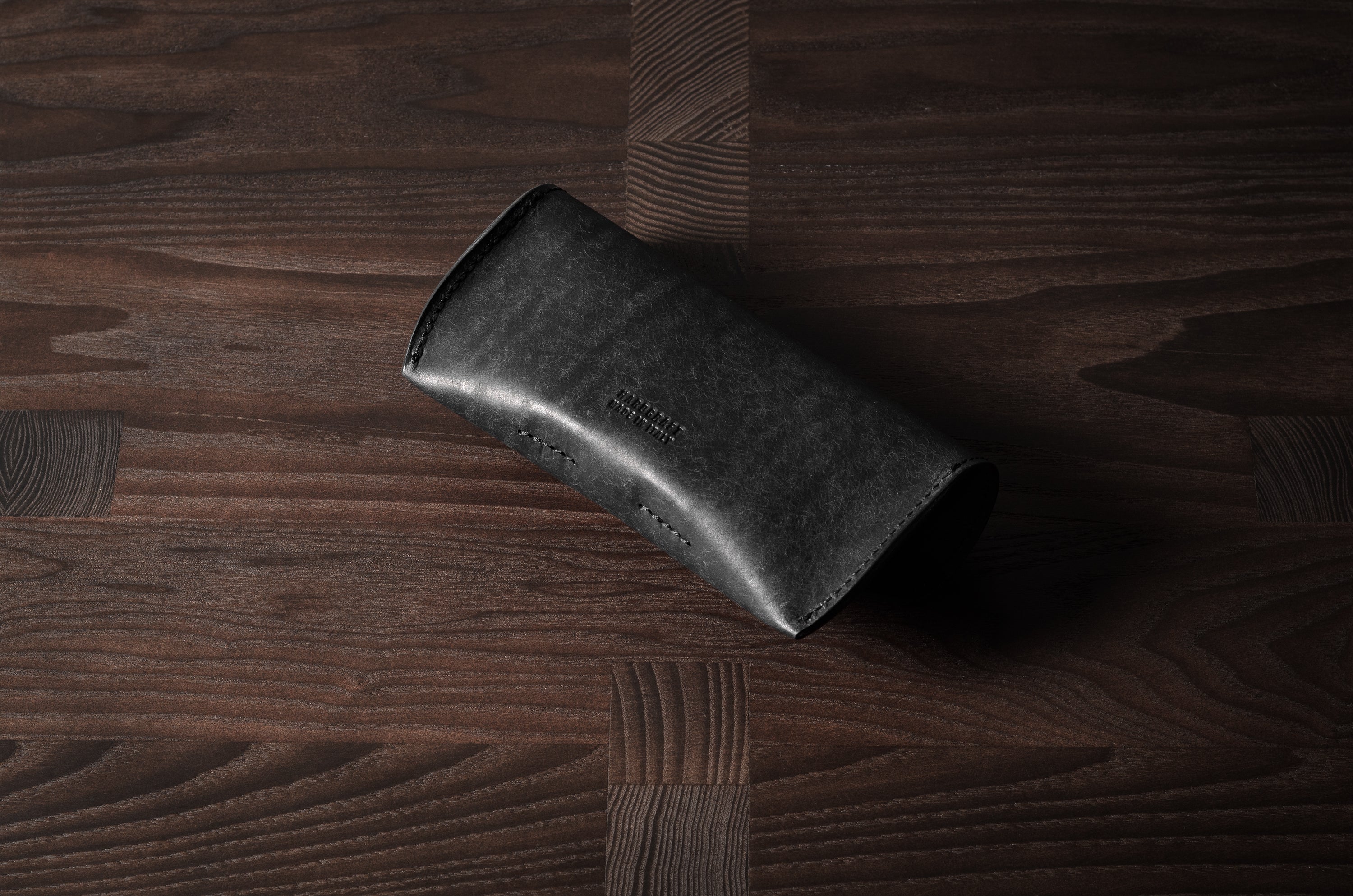 Black leather glasses case on wood background