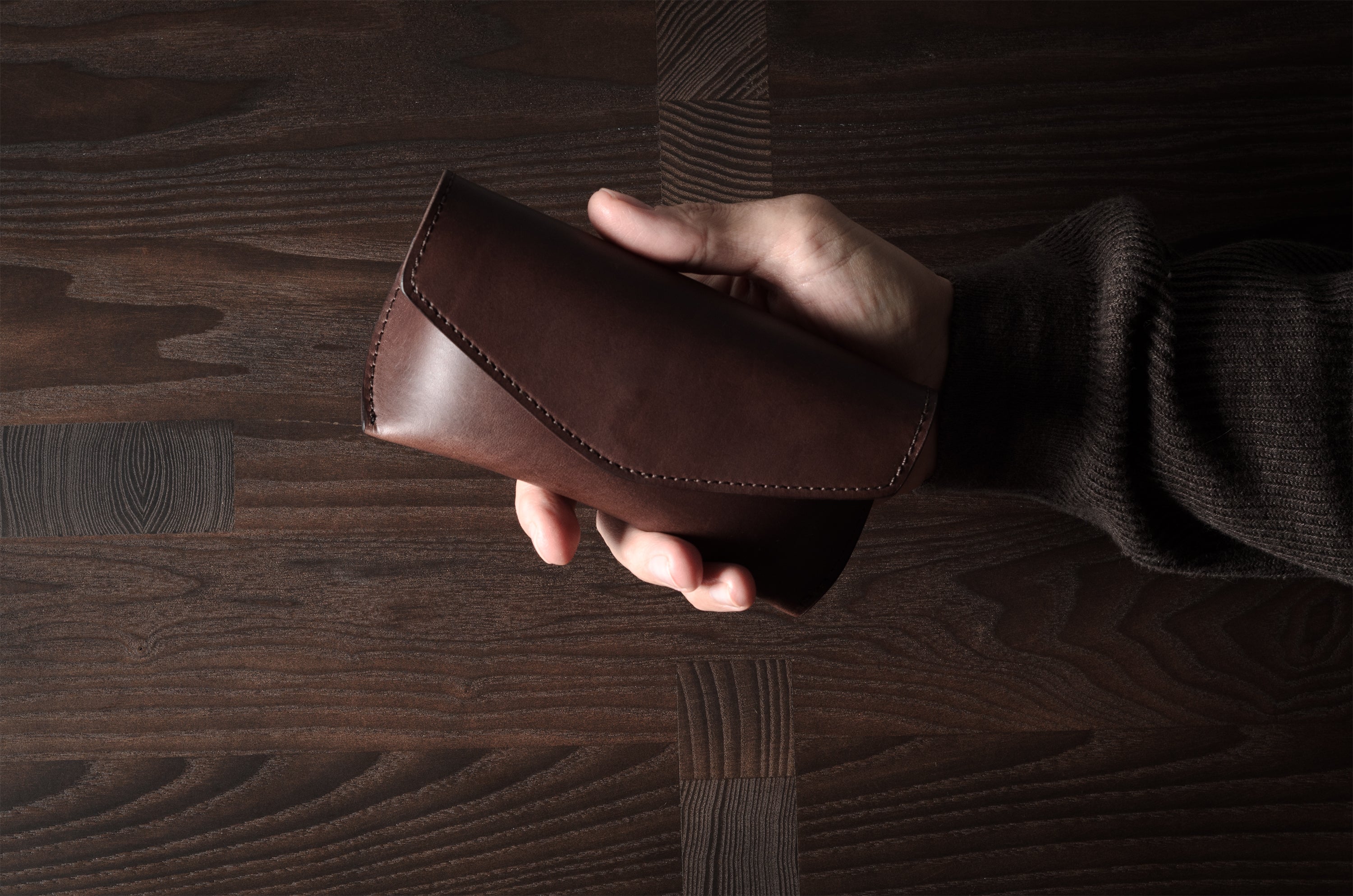 Dark brown leather glasses case in hand