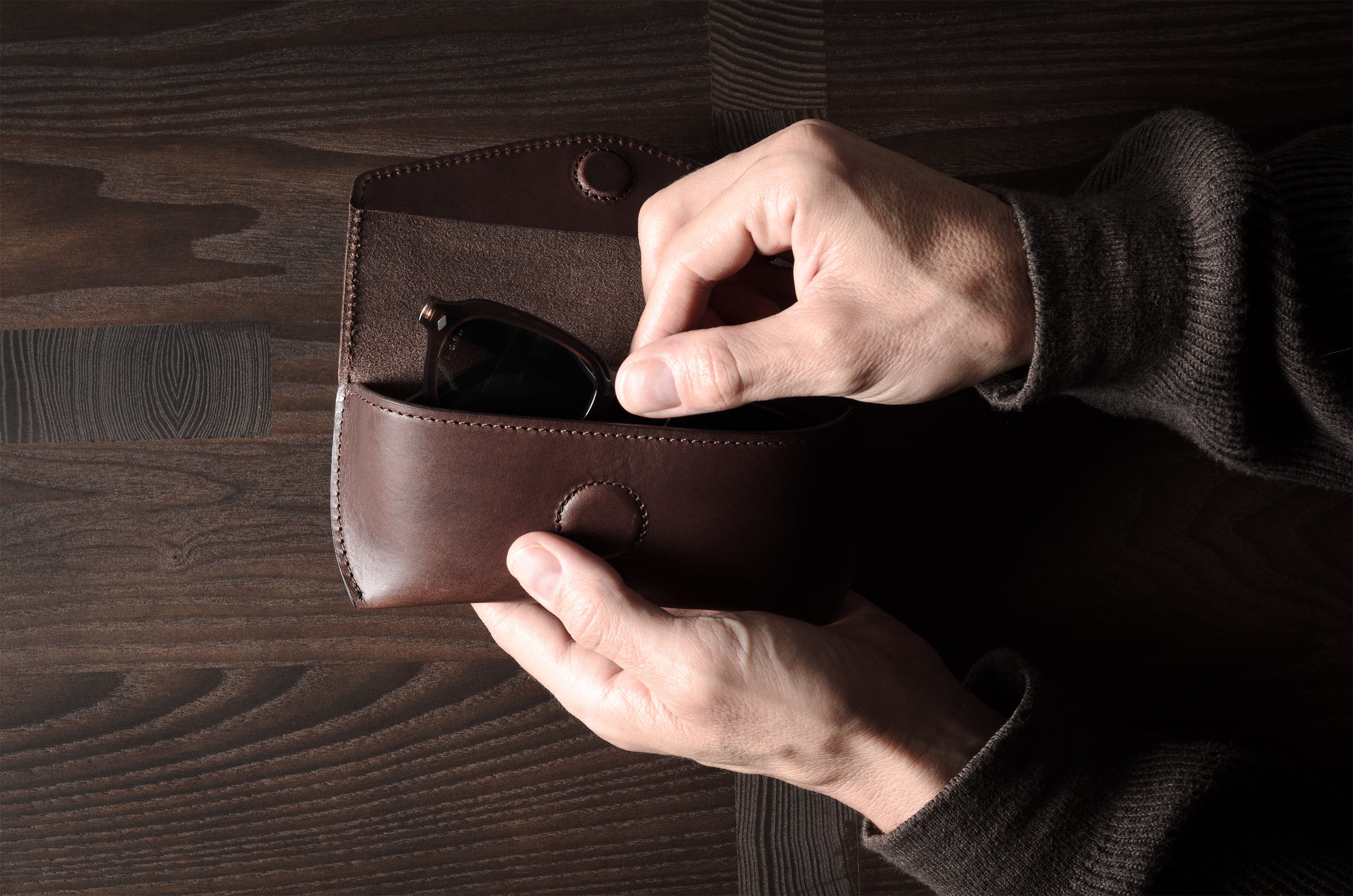 Dark brown leather glasses case in hand