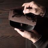 Dark brown leather glasses case in hand