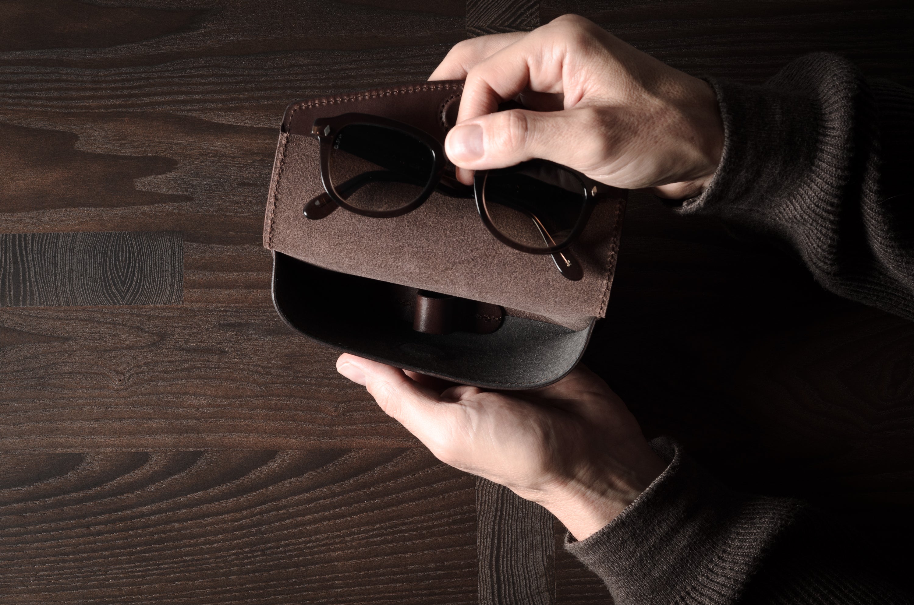 Dark brown leather glasses case in hand