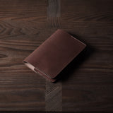 Brown leather passport case on a wooden surface