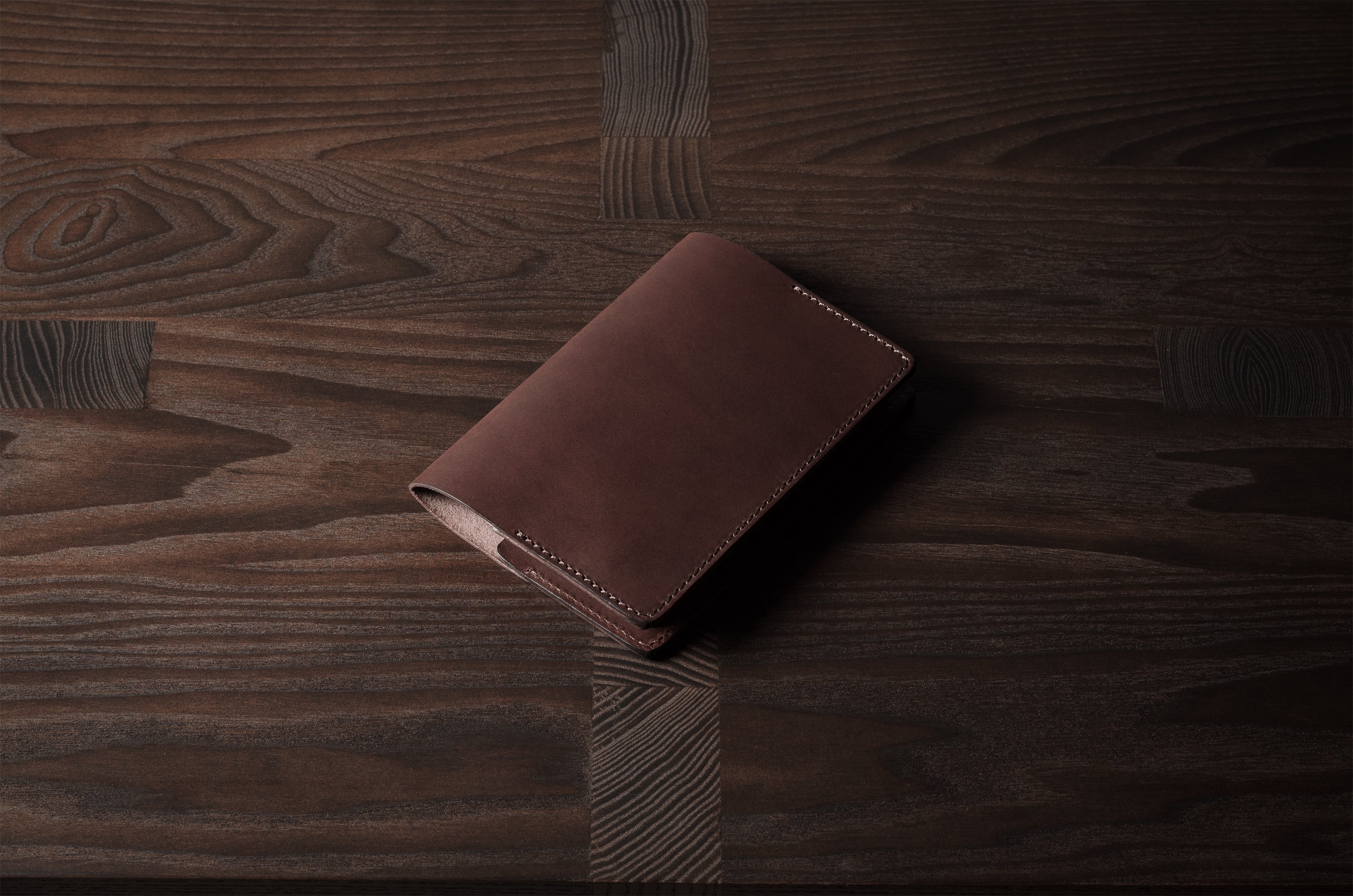 Brown leather passport case on a wooden surface