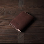 Brown leather passport case on a wooden surface