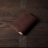 Brown leather passport case on a wooden surface