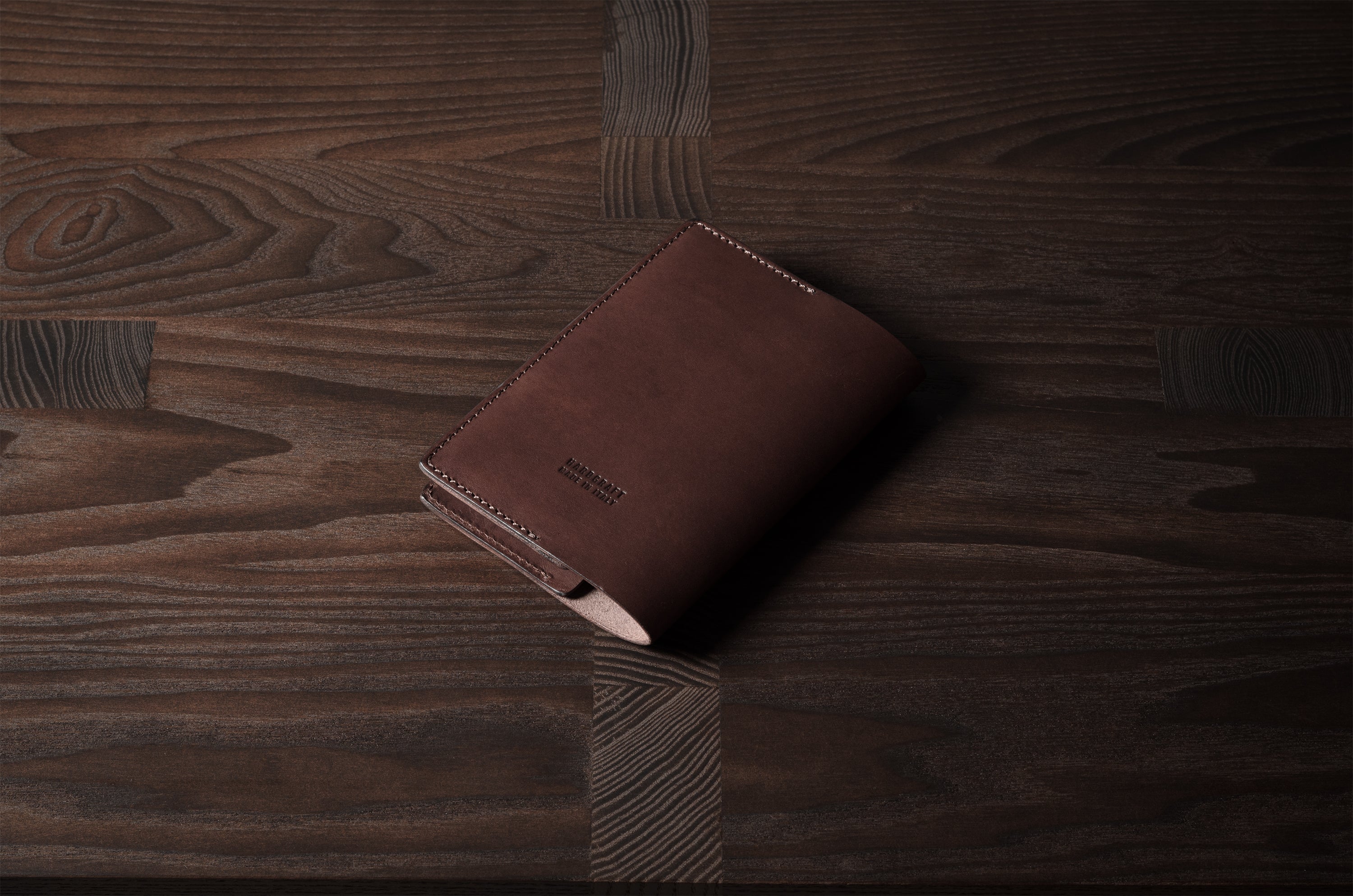 Brown leather passport case on a wooden surface