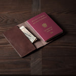 Brown leather passport case on a wooden surface