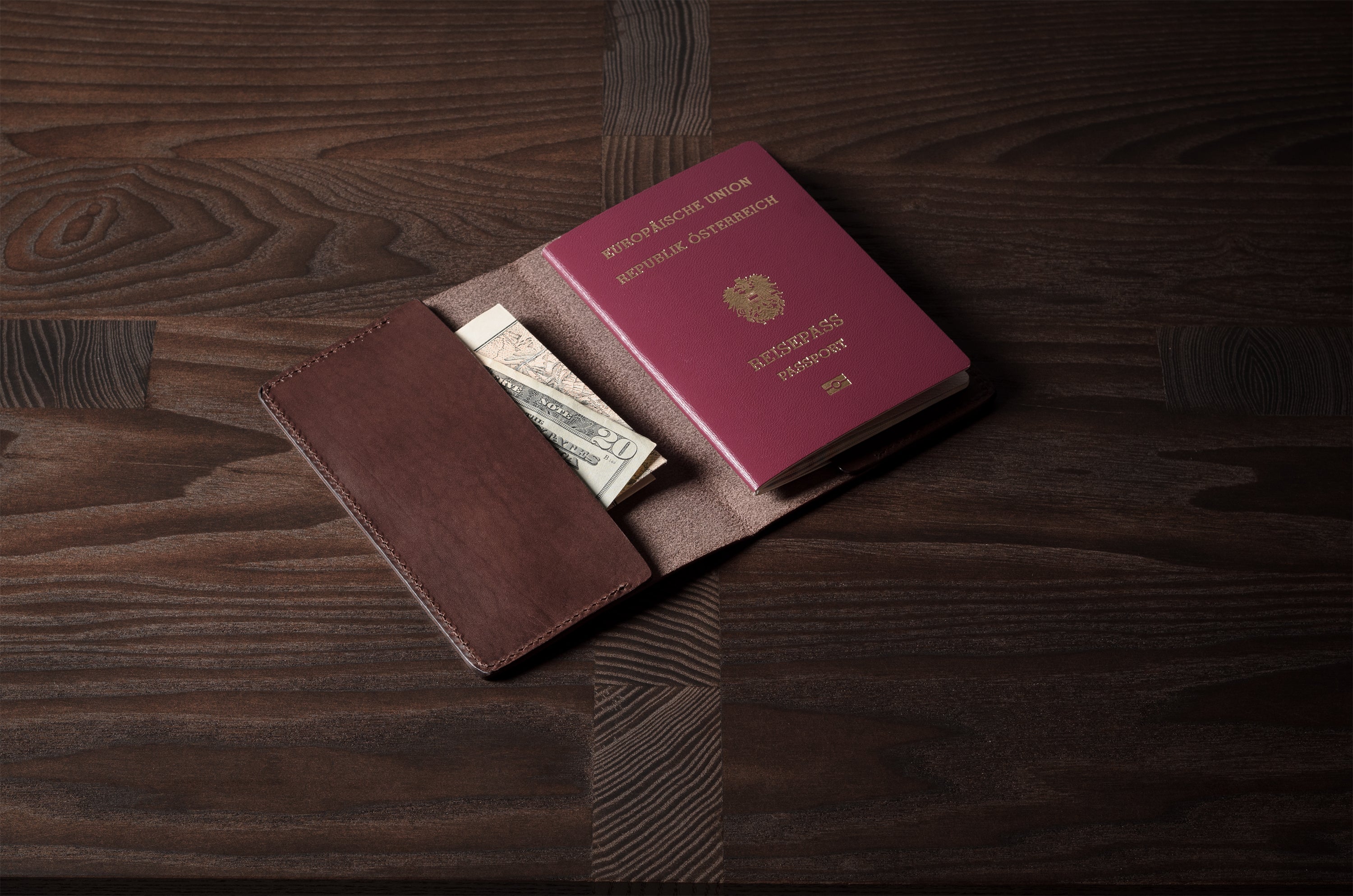 Brown leather passport case on a wooden surface