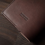 Brown leather passport case on a wooden surface