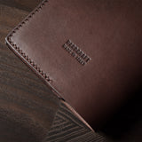 Brown leather passport case on a wooden surface