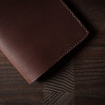 Brown leather passport case on a wooden surface
