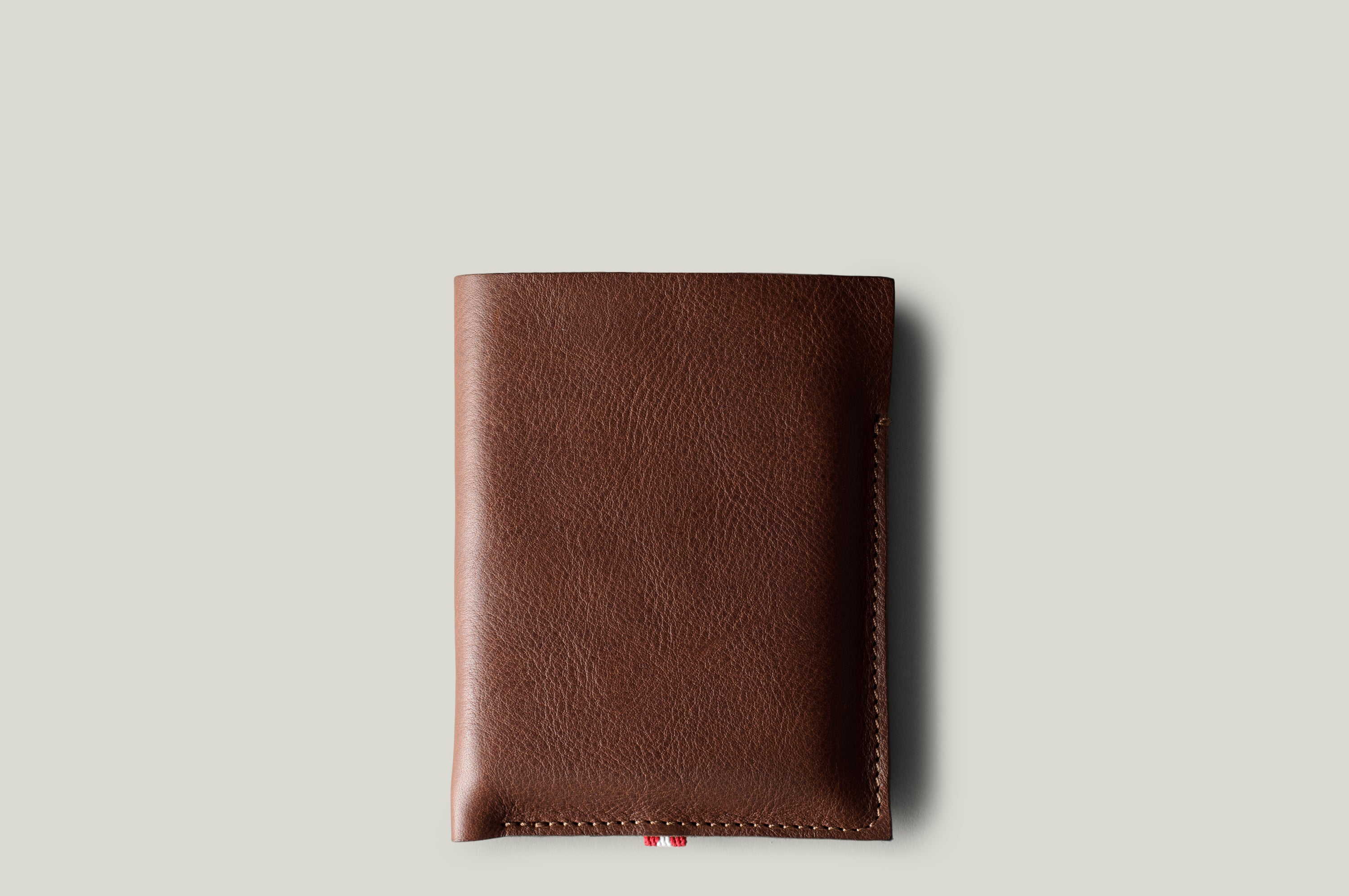 A brown leather iPhone Duo Case with a pebbled texture, shown closed against a solid light gray background.
