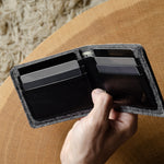 Hand holding an open bi-fold wallet  with cards on a wooden surface
