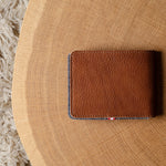 Brown leather bi-fold wallet  on a wooden surface