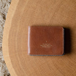 Brown leather bi-fold wallet  on a wooden surface