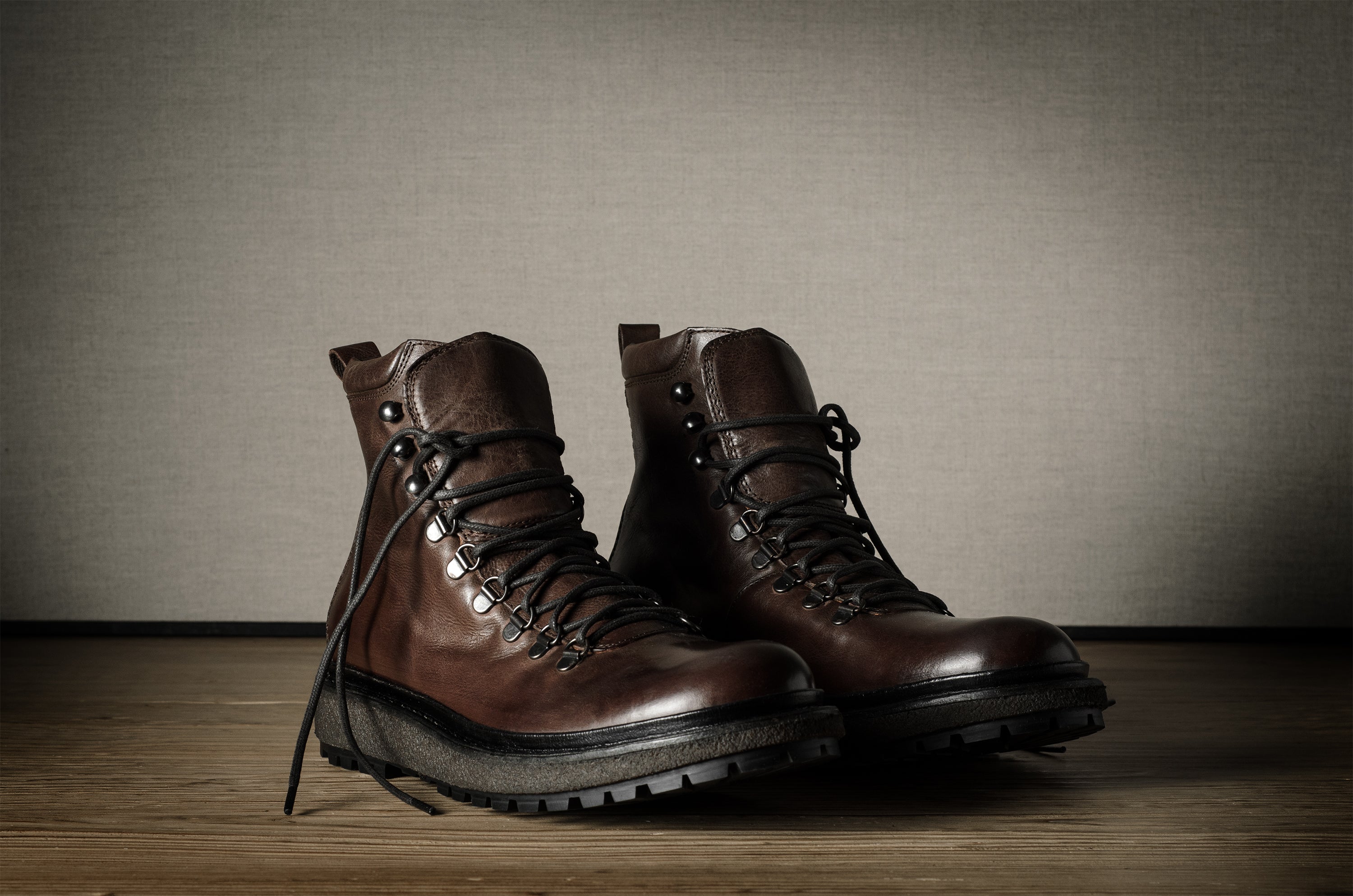 Pair of brown leather boots on a wooden floor with a neutral background