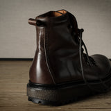Brown leather boot on a wooden surface with a neutral background