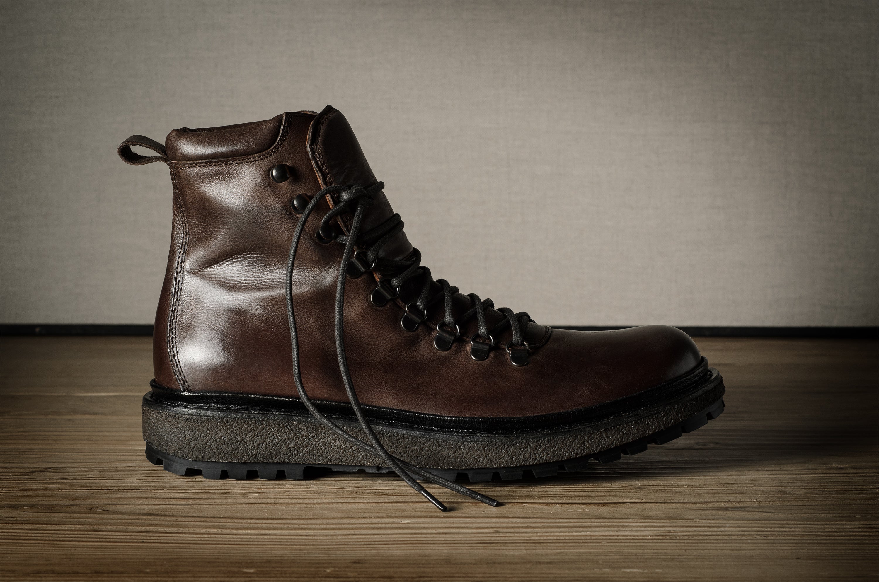 Brown leather boot with black sole on a wooden surface