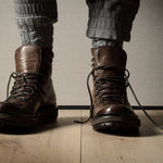 Brown leather boots on a wooden floor with a neutral background
