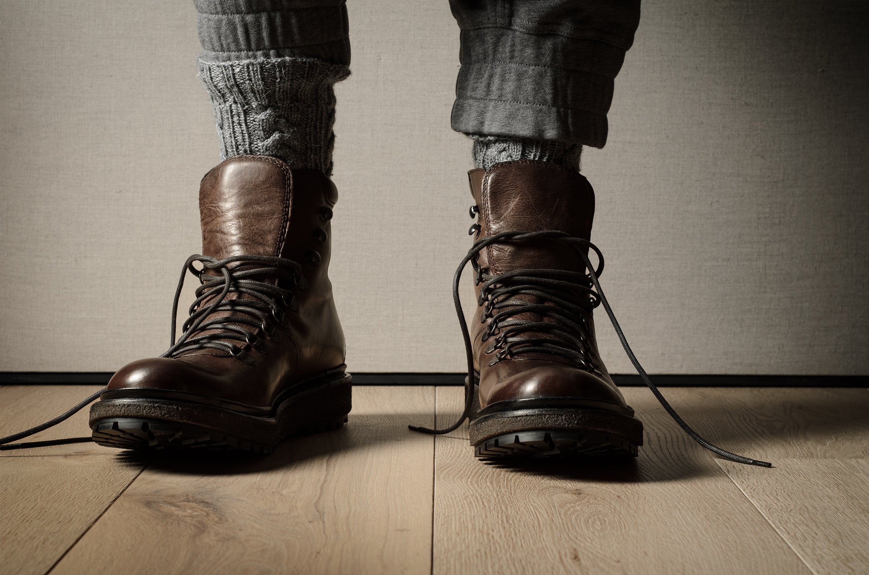 Brown leather boots on a wooden floor with a neutral background