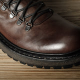 Brown leather boot with black laces on a wooden surface
