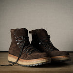 Pair of brown leather boots on a wooden floor with a neutral background