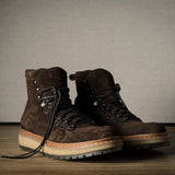 Pair of brown leather boots on a wooden floor with a neutral background