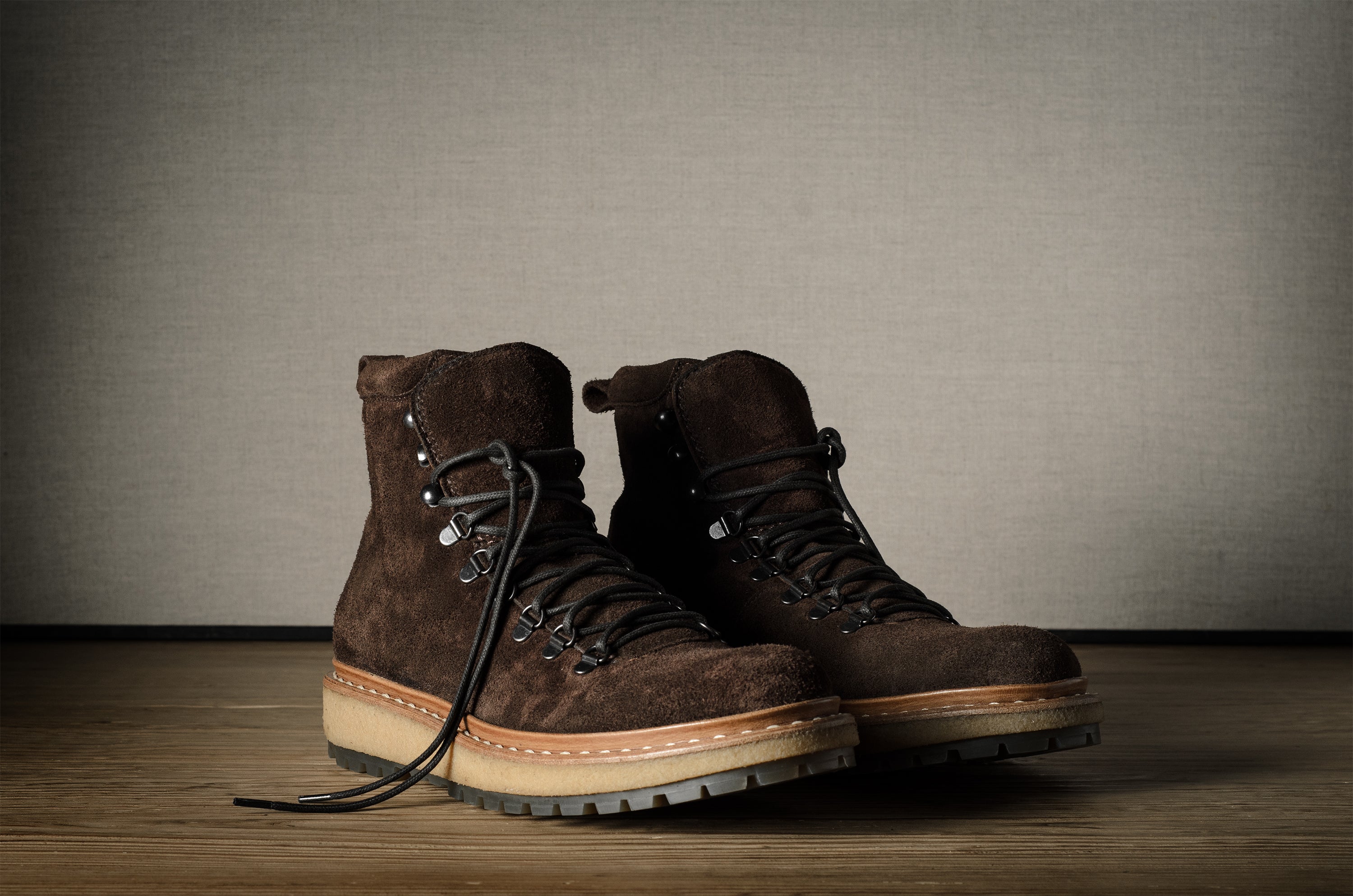Pair of brown leather boots on a wooden floor with a neutral background