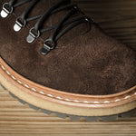 Brown suede boot with a thick sole on a wooden surface