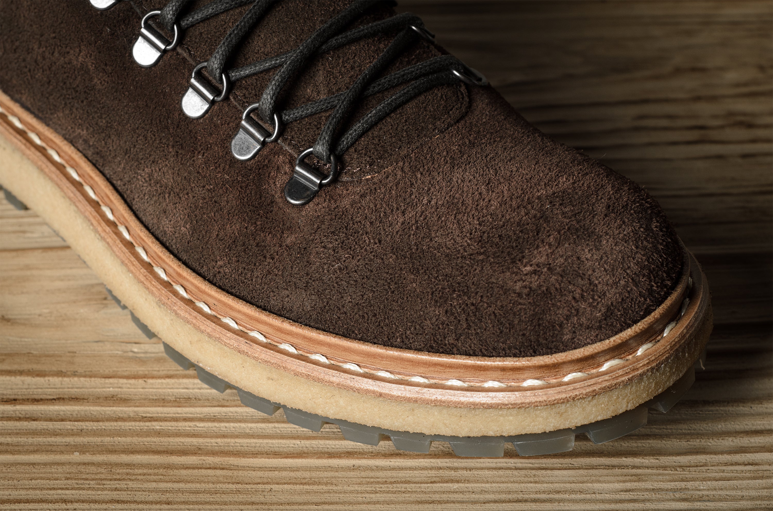 Brown suede boot with a thick sole on a wooden surface