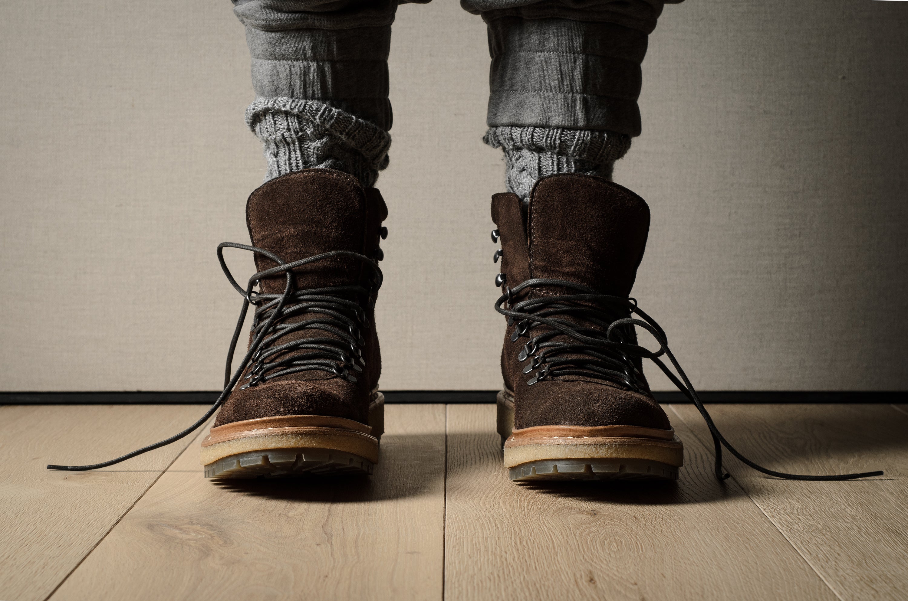 Brown leather boots worn with rolled-up jeans on a wooden floor.