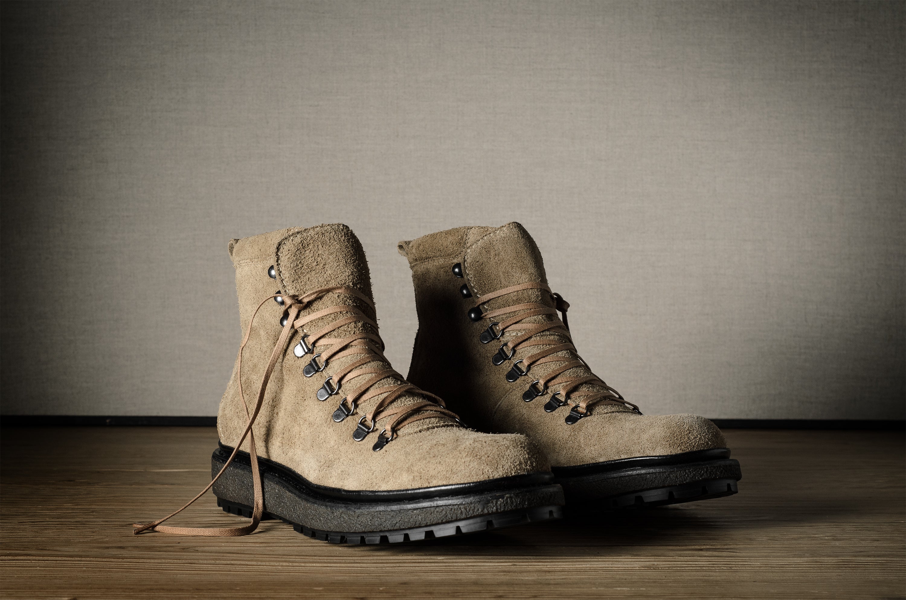 Pair of brown hiking boots on a wooden floor with a neutral background