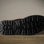 Close-up of a black boot sole with brand logo on a wooden surface.