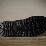 Close-up of a black boot sole with brand logo on a wooden surface.