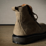 Brown leather boot on a wooden floor with a neutral background