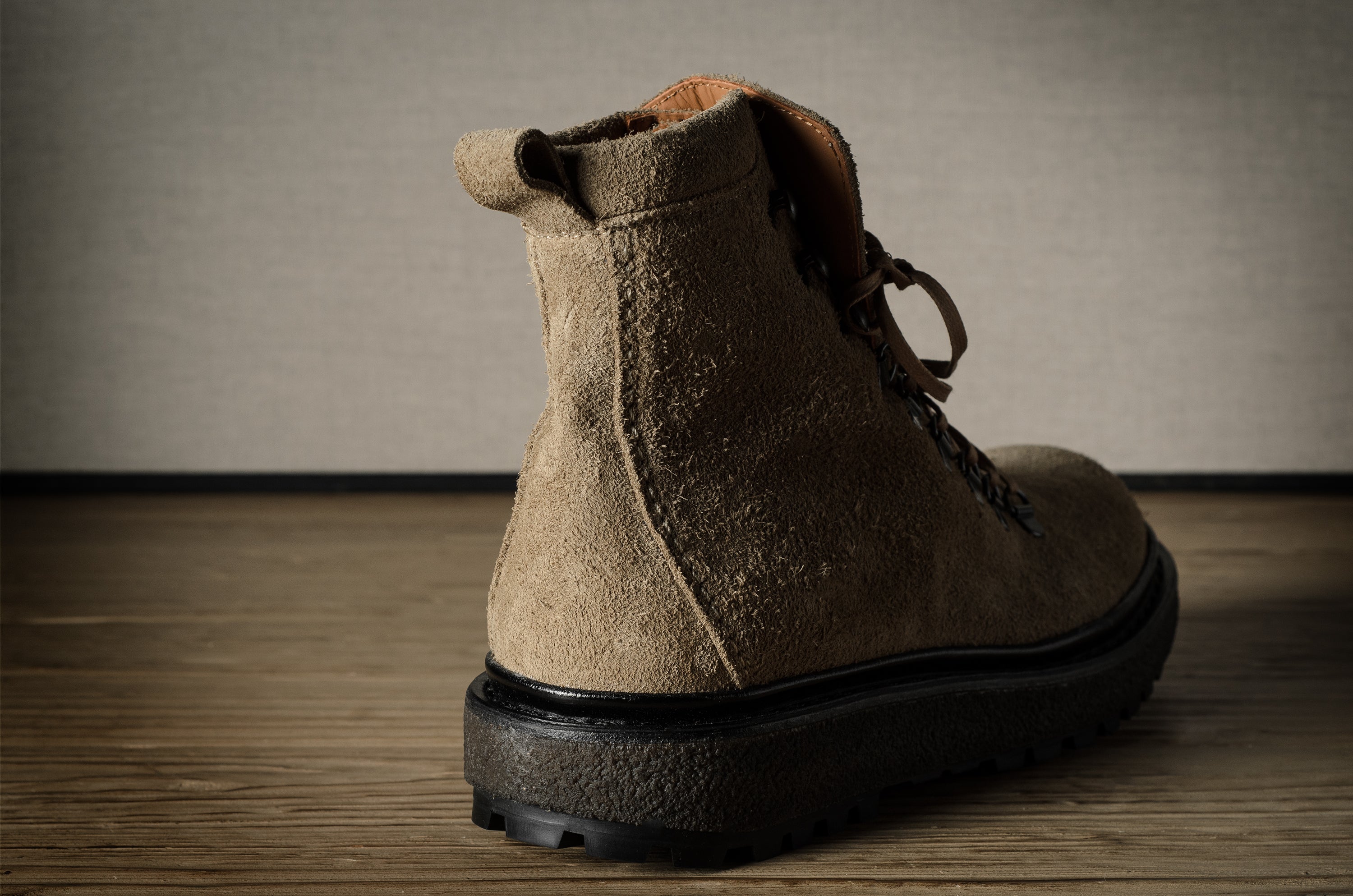 Brown leather boot on a wooden floor with a neutral background