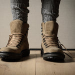 Brown hiking boots on a wooden floor with a neutral background