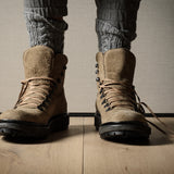 Brown hiking boots on a wooden floor with a neutral background