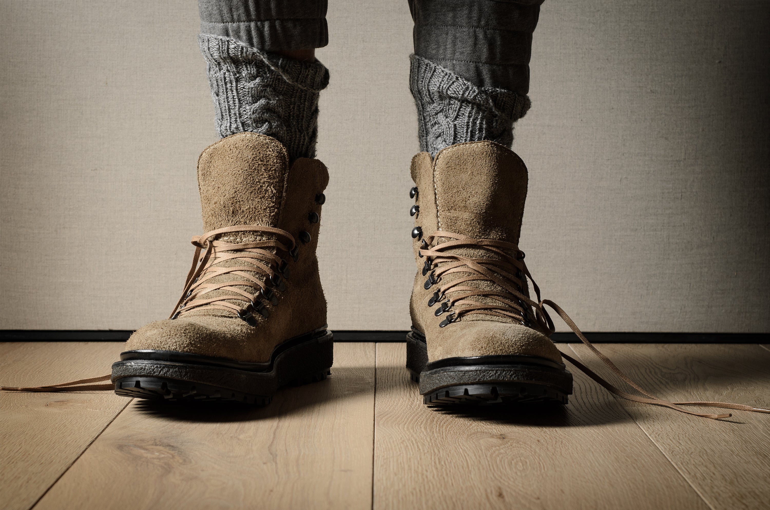 Brown hiking boots on a wooden floor with a neutral background