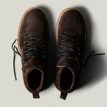 Pair of brown suede boots on a light gray background