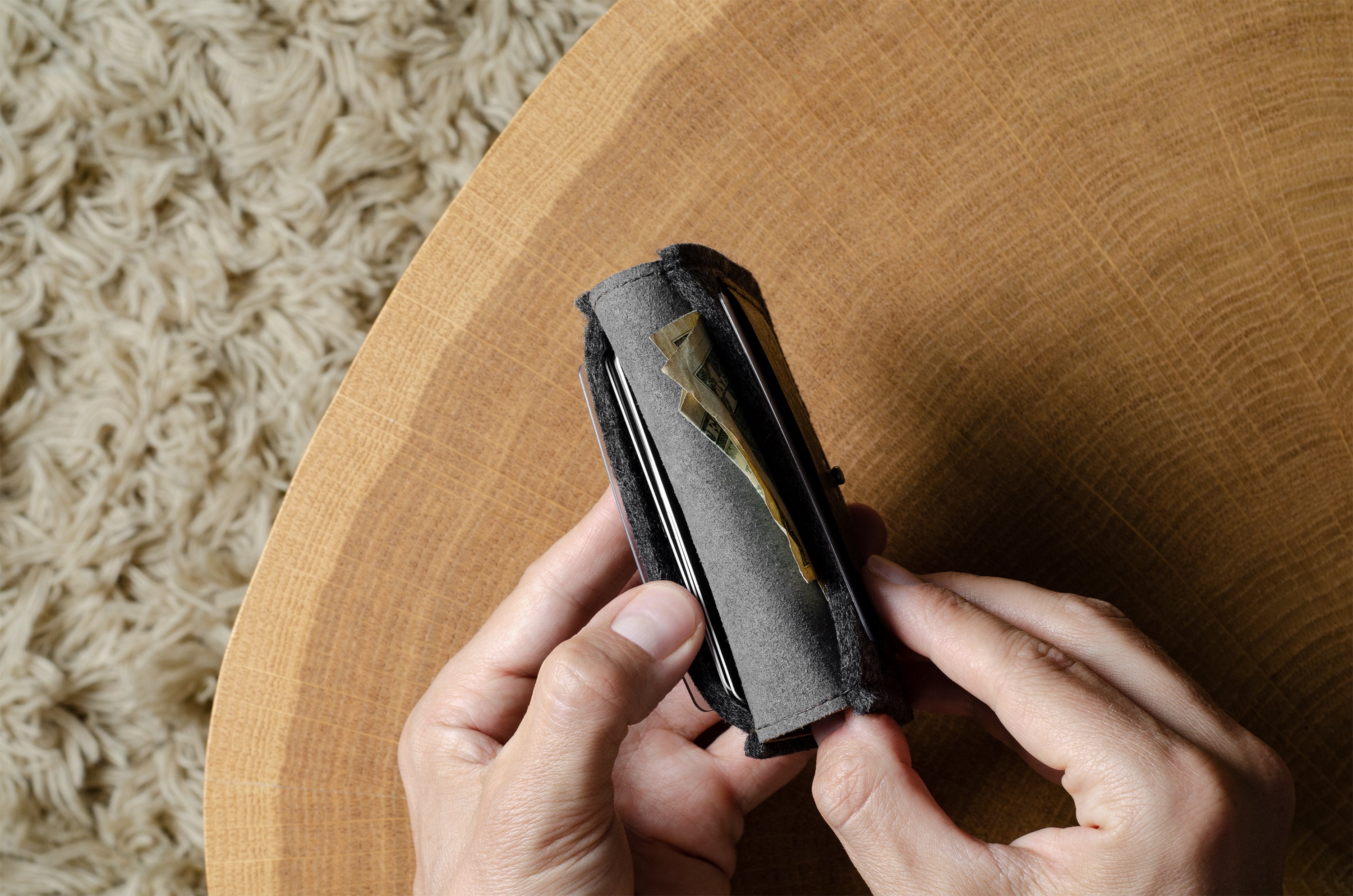 Person holding a wallet on a wooden surface with a textured background