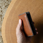 Hand holding a brown leather wallet on a wooden surface